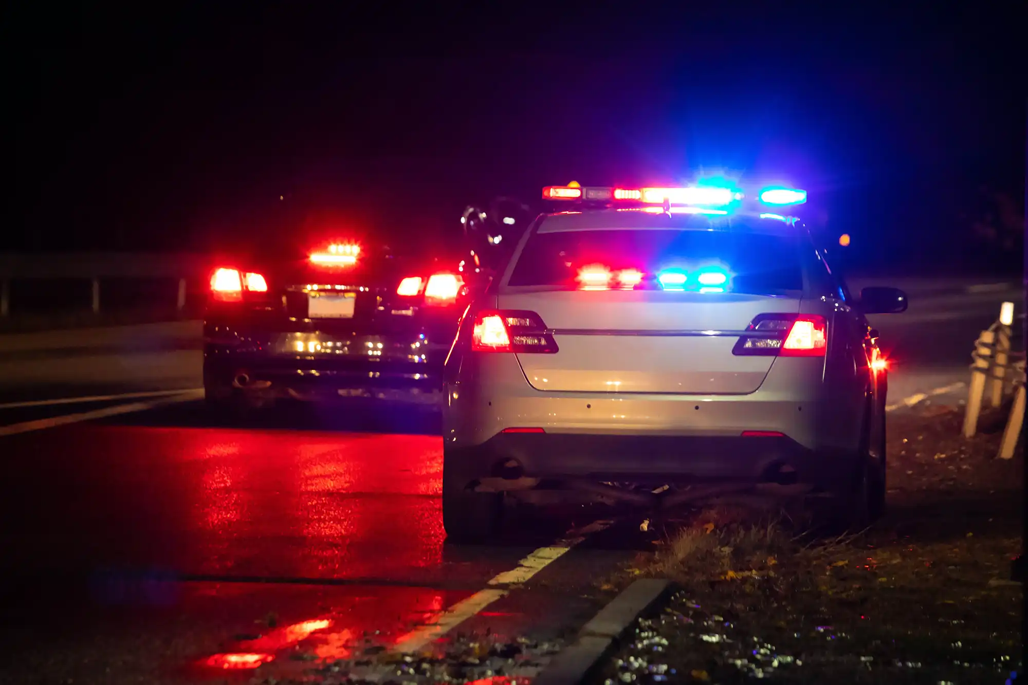 2 police cars on the road with their lights on