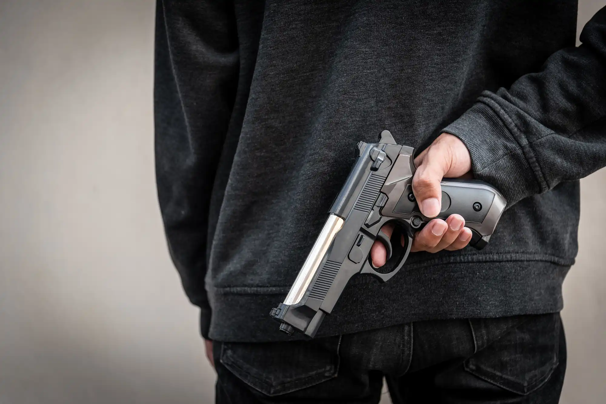 person holding a gun behind their back